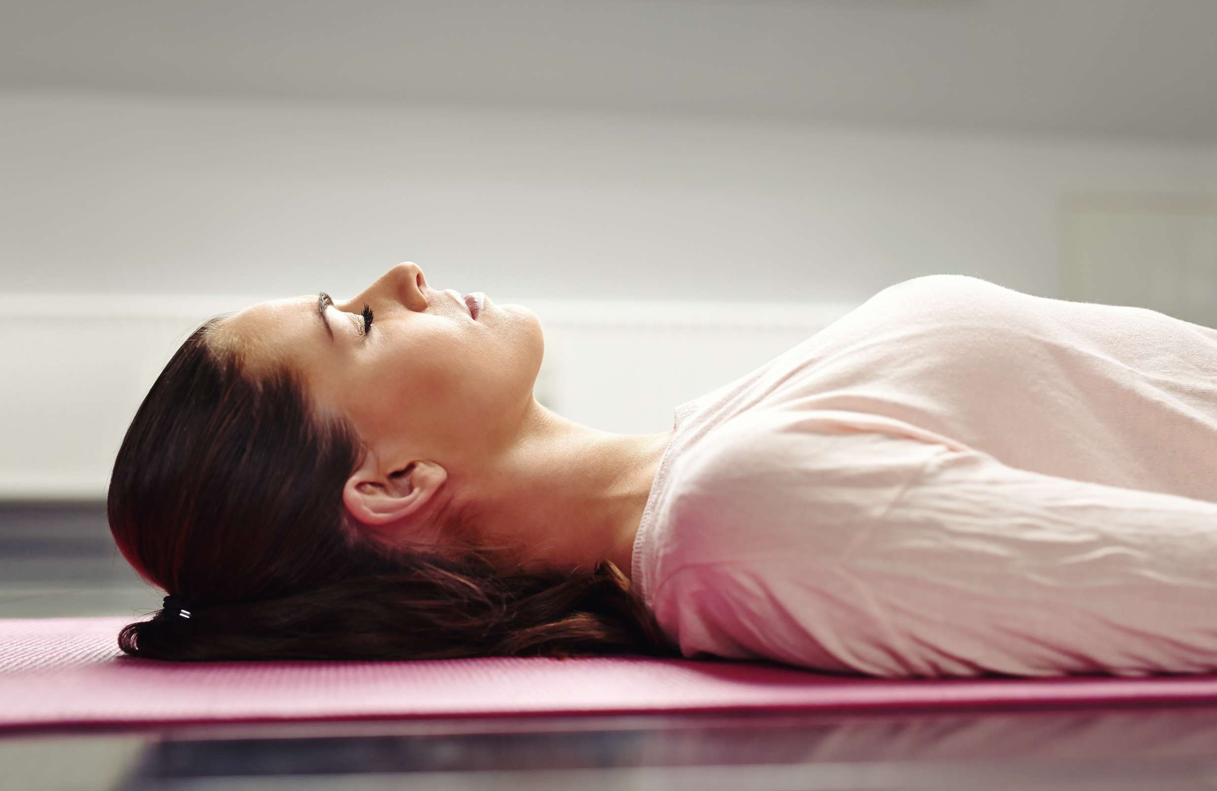 Frau liegend auf Yoga-Matte entspannt ihre Muskeln
